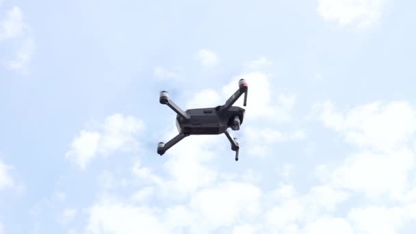 Ένα μεγάλο γκρι drone αιωρείται πάνω από το έδαφος ενάντια σε ένα συννεφιασμένο ουρανό. — Αρχείο Βίντεο