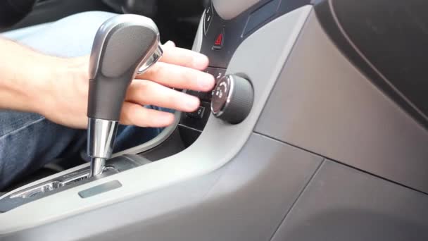 Un homme en jeans bleu appuie sur les boutons du tableau de bord dans une voiture close-up — Video