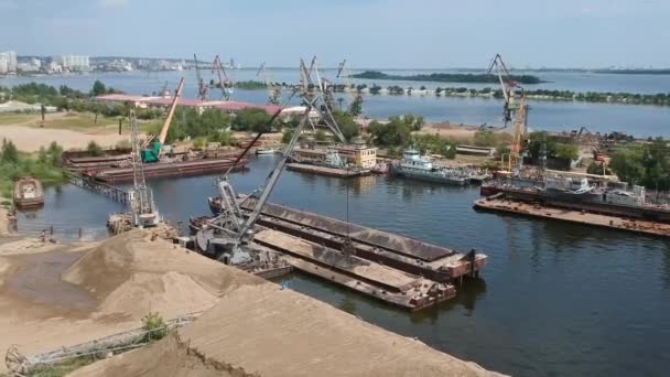 Una grúa de carga descarga arena de una barcaza en un puerto fluvial. Disparos con drones — Vídeos de Stock