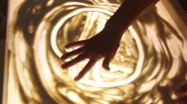 Yaşlı bir kadının elleri kumları çiziyor. Psikolojik yardım