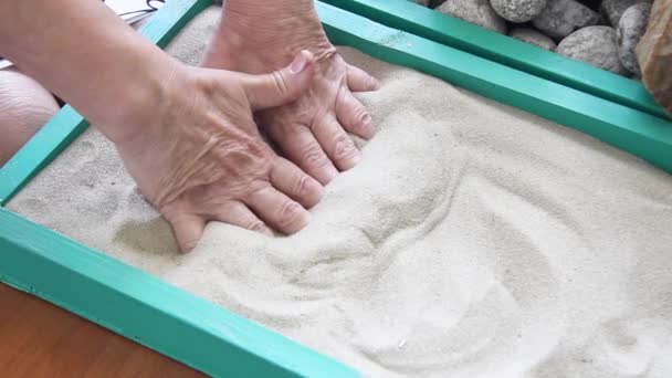 Yaşlı kadınların elleri bir kutuda kumu kazıyor. — Stok video