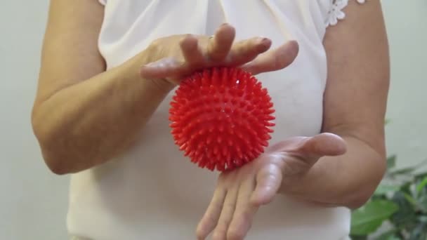 Una mujer en una blusa blanca rueda una bola de masaje de goma — Vídeos de Stock
