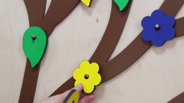 Close-up vrouwelijke handen te verwijderen en zet veelkleurige houten bloemen op houten paneel — Stockvideo
