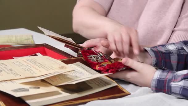 Dłonie kobiet i dzieci sortują medale drugiej wojny światowej. — Wideo stockowe
