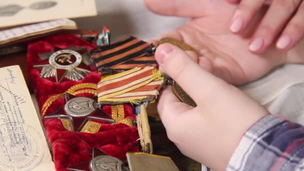 Kvinner og barn går gjennom medaljer fra andre verdenskrig. – stockvideo