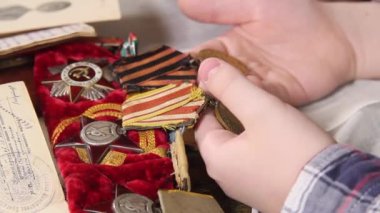 Kadınlar ve çocukların elleri İkinci Dünya Savaşı madalyalarını sıralıyor.
