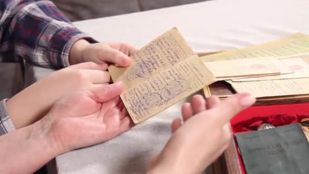 Руки жінок і дітей сортуються за документами та медалями Другої світової війни. — стокове відео