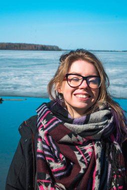 Kameraya gülümseyen gözlüklü genç kadın portresi