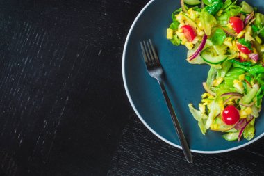 Mavi tabak salata mango, salatalık ve domates üzerinde siyah tablo üstten görünüm