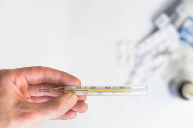 Bir termometre hapları ve ilaçlar ile tutan el