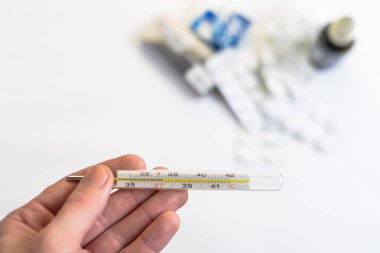 Bir termometre hapları ve ilaçlar ile tutan el