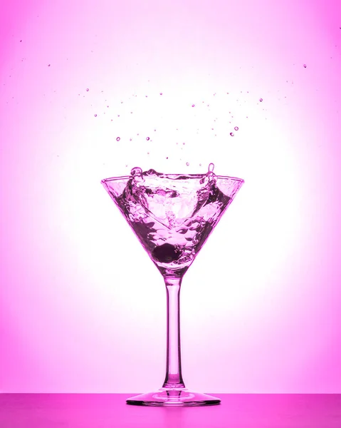 分離した白とピンクのグラデーションの背景にカクテルのマティーニ グラス スプラッシュ — ストック写真