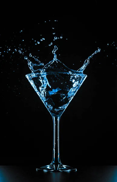 Cocktail martini glass liquid splash on black background