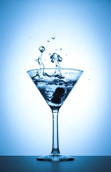分離した白と青のグラデーションの背景にカクテルのマティーニ グラス スプラッシュ — ストック写真