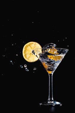 Kokteyl su içki sıçrama limon ile cam izole siyah arka plan üzerine