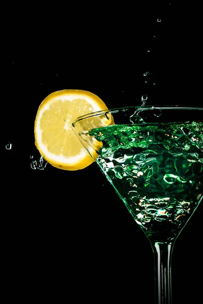 Green cocktail water drink splash in the glass with lemon Isolated on black background