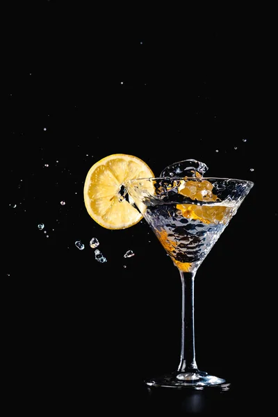 Kokteyl su içki sıçrama limon ile cam izole siyah arka plan üzerine
