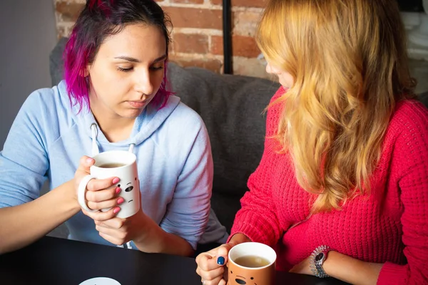 two young women with the cups of tea and coffee talking