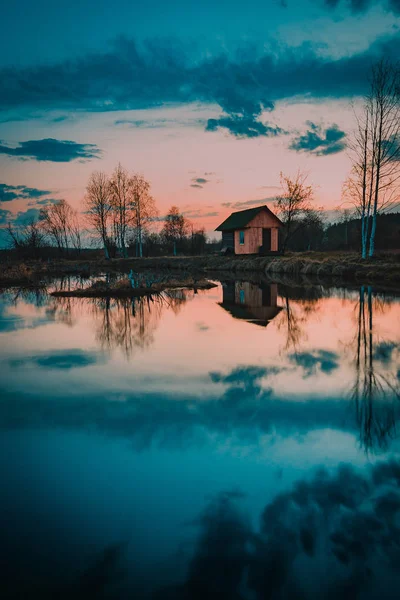 Casa no lago refletida na água no crepúsculo — Fotografia de Stock