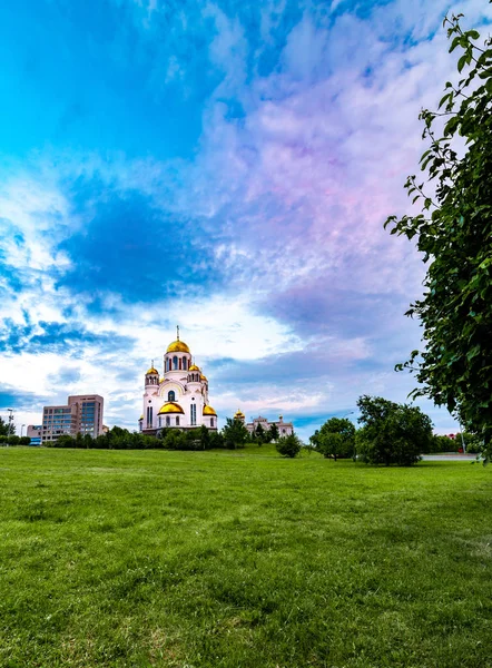 Yekaterinburg' daki Kilise Tapınağı'nın geniş açılı görünümü, Rusya'nın güzel bulutlu gökyüzü ve ön planda yeşil çimenleri ile