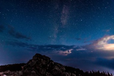 Kayalık dağ ve fırtınalı bulutlar üzerinde gece gökyüzünde Samanyolu galaksi