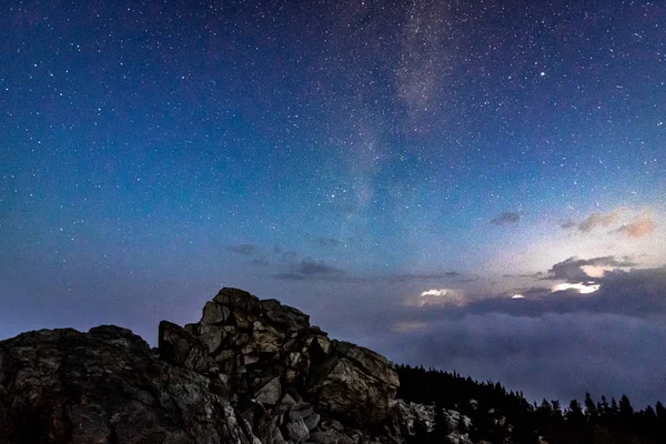 Kayalık dağ ve fırtınalı bulutlar üzerinde gece gökyüzünde Samanyolu galaksi — Stok fotoğraf