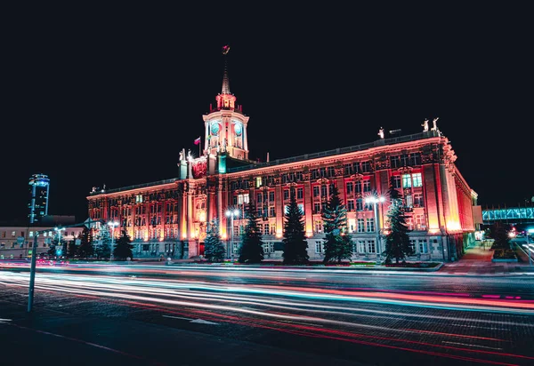 Легкие трассы проезжающих машин перед Екатеринбургской ратушей ночью с темным небом — стоковое фото