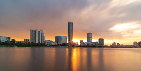 Hermosa puesta de sol nublado en el estanque de la ciudad. Paisaje urbano de larga exposición de Ekaterimburgo, Rusia con rascacielos reflejándose en el agua — Foto de Stock