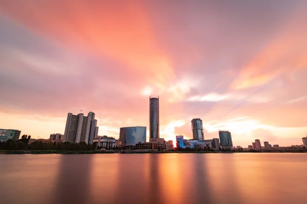 Schönen bewölkten Sonnenuntergang am Stadtweiher. Langzeitbelichtung Stadtbild von yekaterinburg, Russland mit Wolkenkratzern, die sich im Wasser spiegeln — Stockfoto