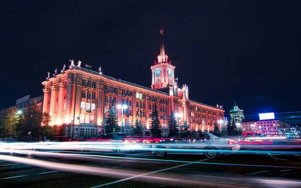 Senderos de luz de los coches que pasan frente al ayuntamiento de Ekaterimburgo por la noche con cielo oscuro Fotos De Stock Sin Royalties Gratis