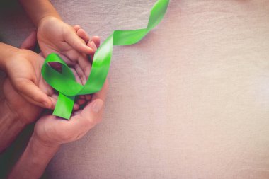 Adult and child hands holding Lime GreenRibbon, Mental health awareness and Lymphoma Awareness clipart