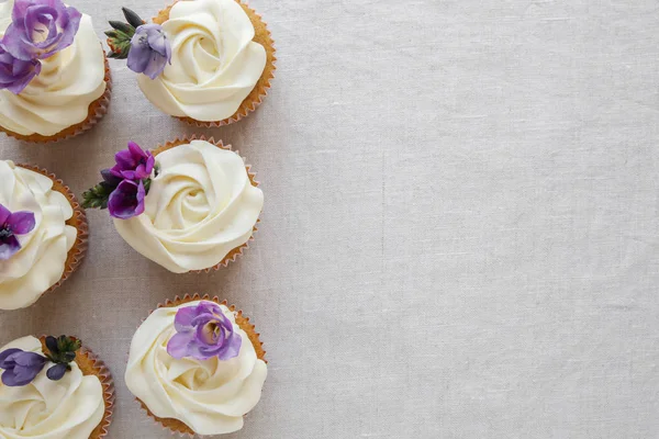 紫色の食用花とバニラ カップケーキのフロスティング コピー領域の背景 — ストック写真