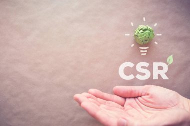 Yeşil kağıt ampul Csr ile üzerinde eller, kurumsal sosyal sorumluluk