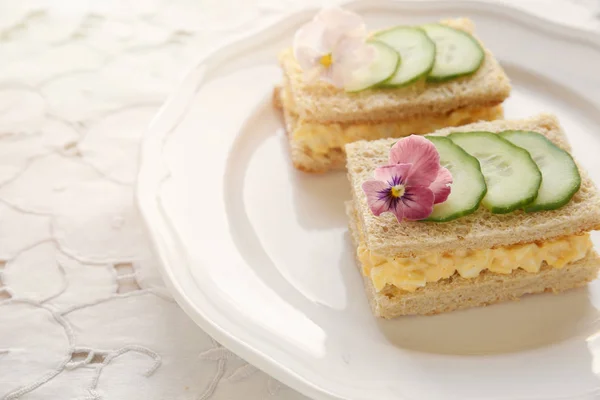 Egg and cucumber afternoon tea sandwiches with edible flowers, toning