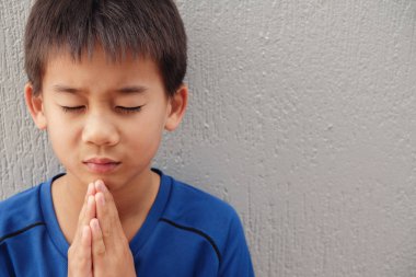 Asyalı çocuk duvar arka plan kapalı gözler ile dua 