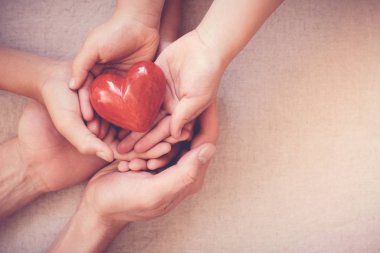 Kırmızı kalp, sağlık sigortası ve bağış kavramı holding yetişkin ve çocuk eller