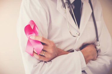 Doktor pembe kurdele, meme kanseri bilinçlendirme, Ekim pembe kavramı sembolü tutan boynunda steteskop ile 