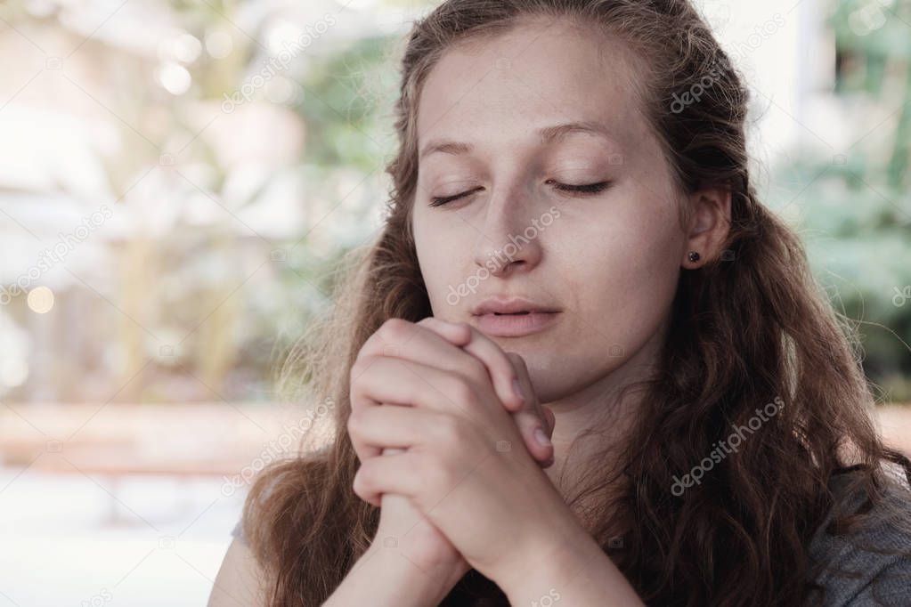 Young woman praying with eyes closed