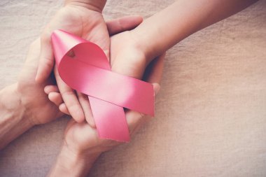 hands holding pink ribbon, breast cancer awareness, October pink concept clipart