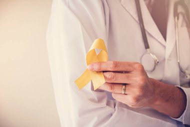 sarı altın şerit, sarkom farkındalık, çocukluk kanseri bilinçlendirme tutan doktor el