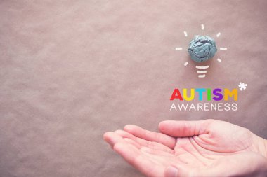 Mavi kağıt ampul ve eller, bulmaca dünya otizm farkındalık günü