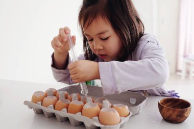 Mixed Asian girl planting seeds into eggshells, eco gardening clipart