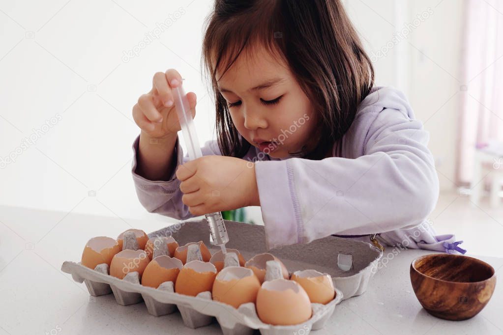 Mixed Asian girl planting seeds into eggshells, eco gardening