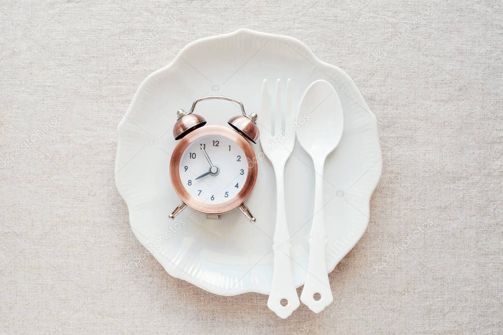 clock on plate and tape measure, intermittent fasting diet concept