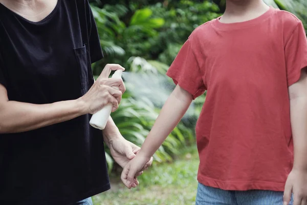 Genitore spruzzando insetto repellente sulla pelle del figlio, utilizzando zanzara — Foto Stock