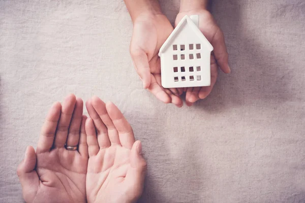 Volwassen en kind handen houden witte huis, familie thuis en onthaal — Stockfoto