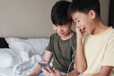 Ara çocuklar akıllı telefon ve paylaşım kulaklıklar kullanarak, dinleme 