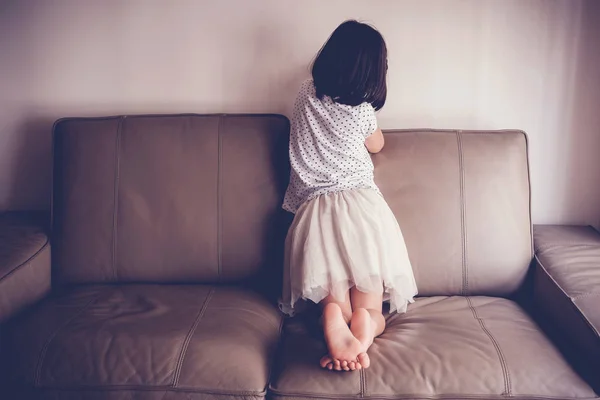 Ragazzina solitaria sul divano di casa, austerismo e hea mentale bambino — Foto Stock