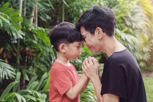 Jeune garçon asiatique priant avec sa mère dans le parc à l'extérieur, fa — Photo