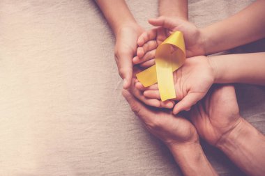 sarı altın kurdele tutan yetişkin ve çocuk elleri, Sarcoma Awa